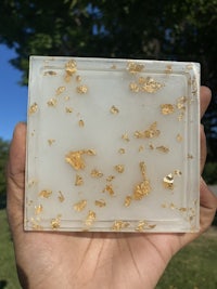 a person holding a piece of white marble with gold flakes on it