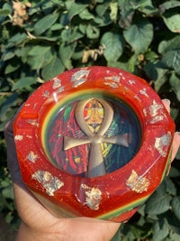 a red and gold ashtray with an egyptian symbol on it