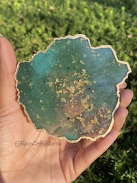 a person holding a piece of green and gold agate