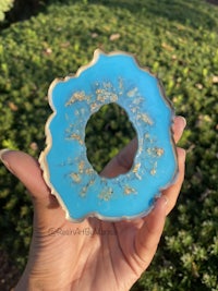 a person holding a blue and gold agate ring