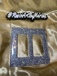 a silver glitter switch plate with a logo on it