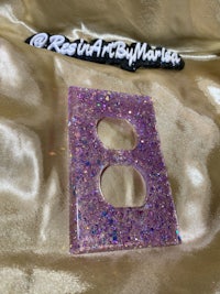 a purple glitter light switch cover on a gold background